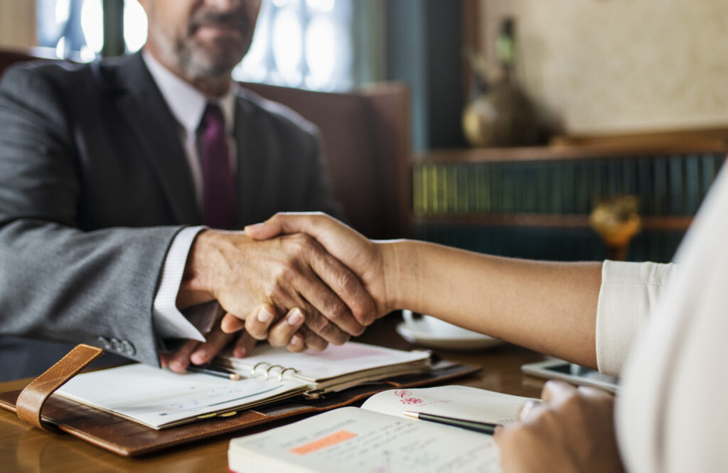 Aperto de mãos entre advogado e cliente sobre a mesa de reunião do escritório